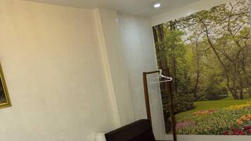 Una habitación de hotel con una cama, un sofá, un cuadro de un jardín y una toalla con una etiqueta.