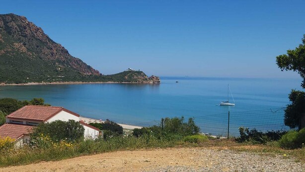 A coastal view with a building, a clear sky, and a calm sea.