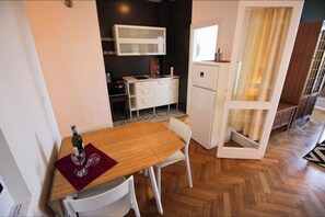 A compact kitchen with a dining area, a refrigerator, and a window with curtains.