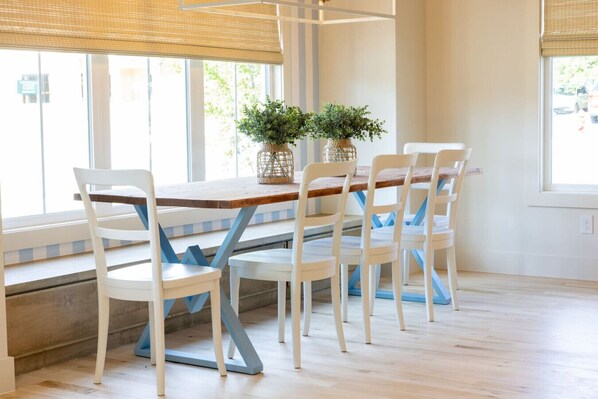 A dining area with a wooden table and white chairs with blue cushions. There are two potted plants on the table. - Luxury 4BR |Sleeps 9 | New Build | Family Friendly (Broken Arrow)