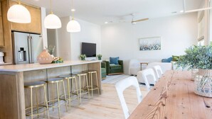 Une cuisine moderne avec un îlot central en bois, des tabourets de bar et des luminaires suspendus.