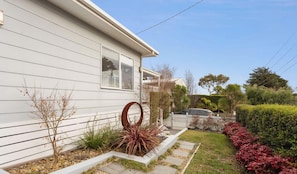 Una casa residenziale con facciata bianca, un giardino anteriore con aiuola circolare e un'auto parcheggiata nel vialetto.