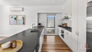 A modern kitchen with a central island, stainless steel appliances, and a view to the outside. - Chloe Retreat in Cowes (Cowes)