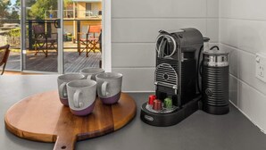 A modern kitchen with a coffee machine, a wooden board with mugs, and a view of the outdoors through glass doors. - Chloe Retreat in Cowes (Cowes)