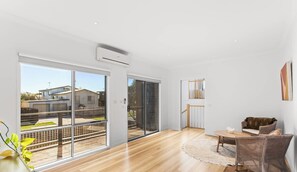 A spacious living area with a wooden floor, a sofa, a dining table, and large sliding glass doors leading to a balcony. - Chloe Retreat in Cowes (Cowes)