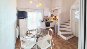 A modern kitchen with white cabinets, a glass dining table, and hanging pendant lights. - Villa 3 façades garden terrace and sea view, swimming pool and club house, tennis court (La Croix-Valmer)
