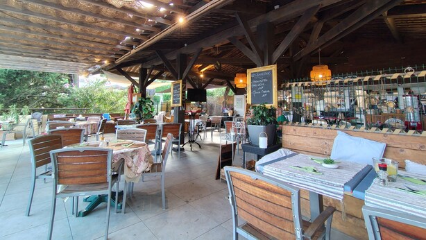 An outdoor café with wooden tables and chairs, a bar area with various items, and a chalkboard menu. - Villa 3 façades garden terrace and sea view, swimming pool and club house, tennis court (La Croix-Valmer)