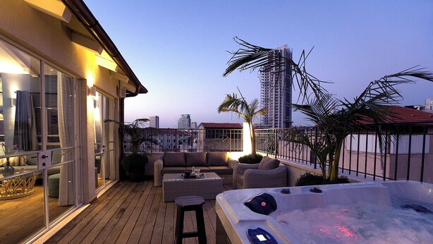 A deck with a hot tub, outdoor seating, and a view of the city skyline. - Molcho Neve Tzedek (Tel Aviv)