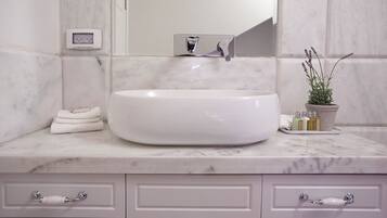 Un baño con lavamanos blanco, encimera de mármol y una planta en maceta.