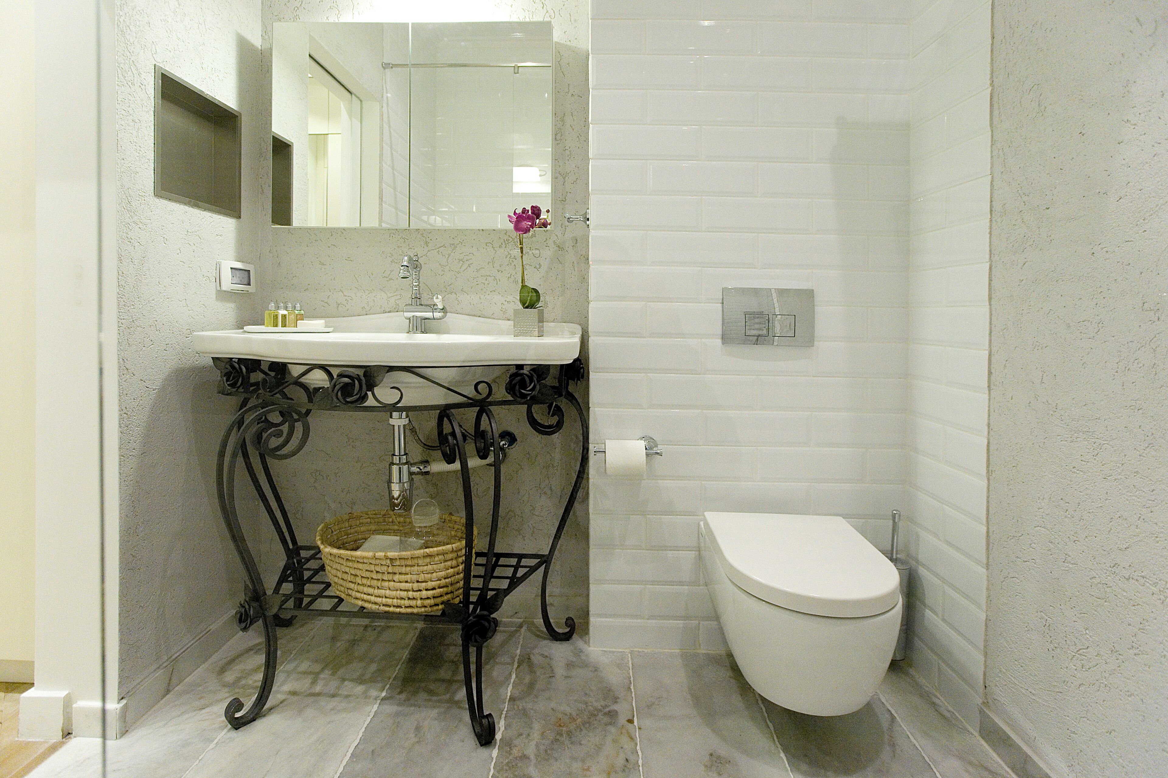 A bathroom with a white sink, a toilet, and a mirror.
