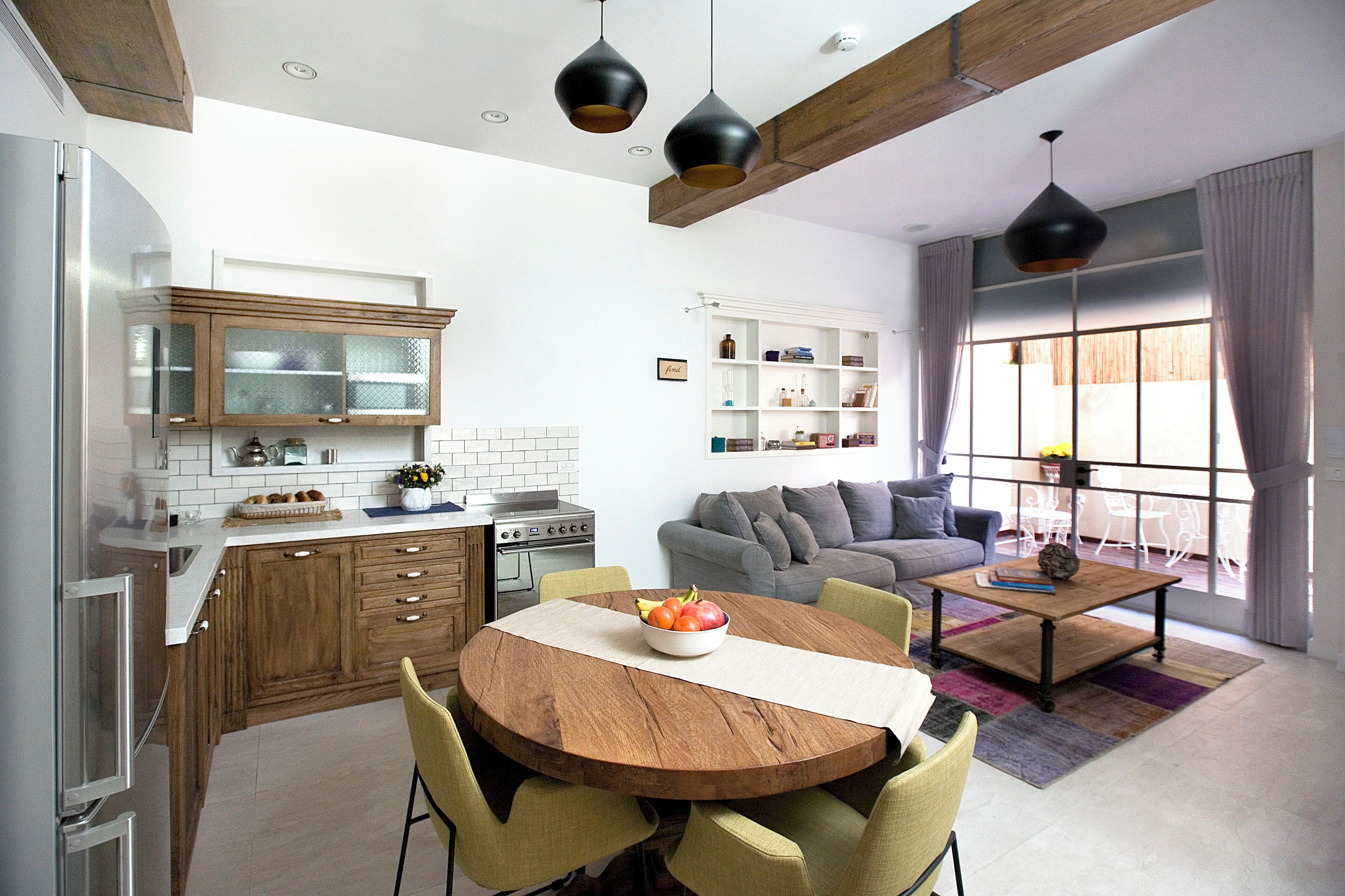 Una cocina moderna con armarios de madera, una mesa de comedor con sillas y un amplio ventanal con cortinas.