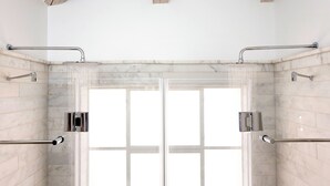 A modern shower with glass doors, chrome fixtures, and a marble-tiled wall. - Molcho Neve Tzedek (Tel Aviv)