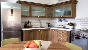 Una cocina con armarios de madera, un refrigerador de acero inoxidable, una estufa y un tazón de frutas sobre la mesa.