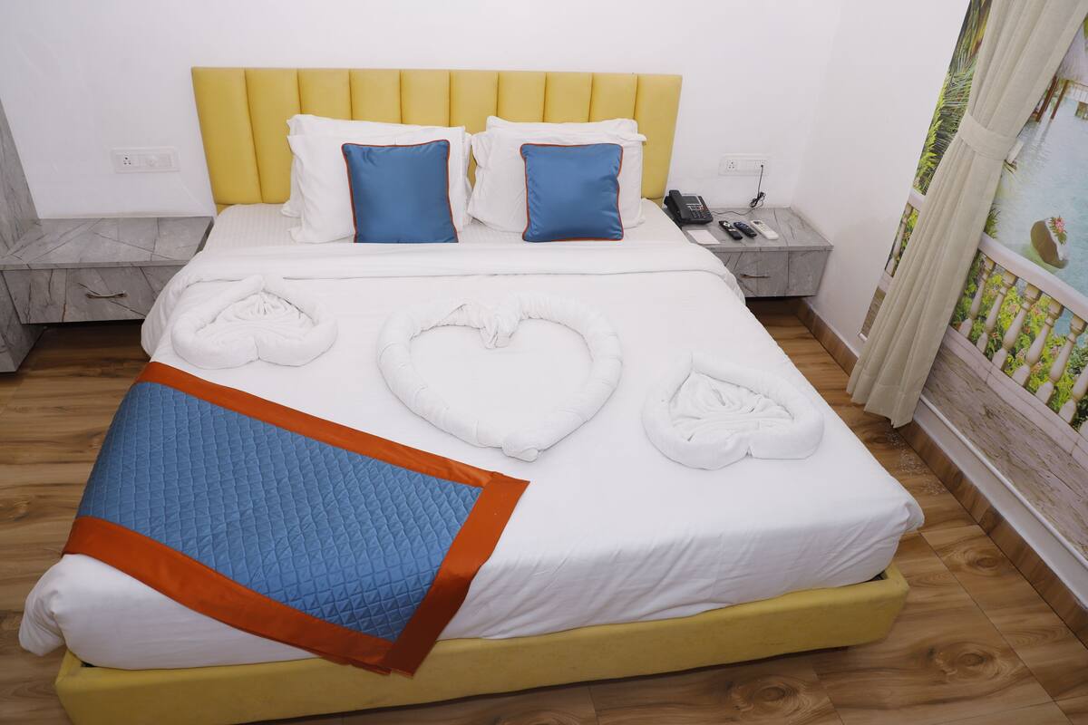 Una habitación de hotel con cama, mesita de noche y cortina que da a un jardín.