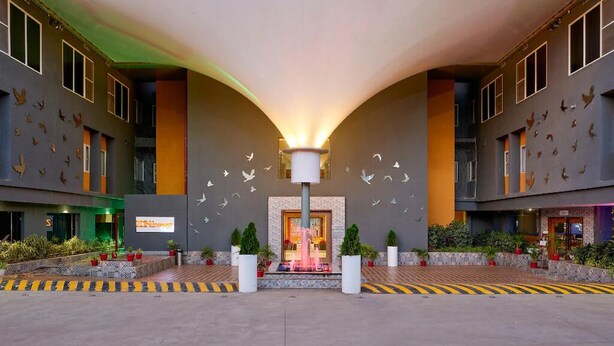 Un hall de hotel con una lámpara central, una recepción y una entrada amplia.
