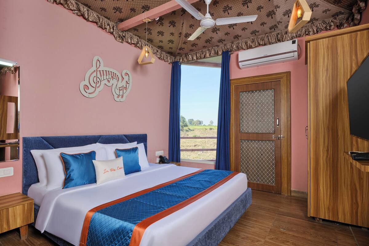 Un dormitorio con una cama grande, un ventilador de techo, un equipo de aire acondicionado y vistas al exterior.
