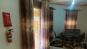 Una sala de estar con un sofá, una mesita, una alfombra y un extintor en la pared.