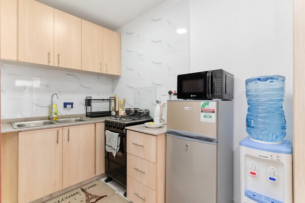 Cocina compacta con armarios de madera, estufa, microondas y refrigerador.