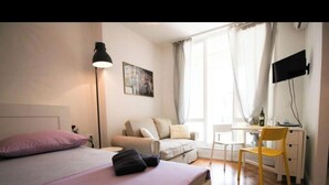 A bedroom with a bed, a desk, a chair, a lamp, and a TV. - Luxury living studio apartment with balcony in Split near center (Split)