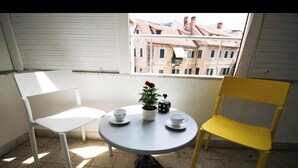 A small round table with a white chair and a yellow chair, a potted plant, and a cup on the table. - Luxury living studio apartment with balcony in Split near center (Split)