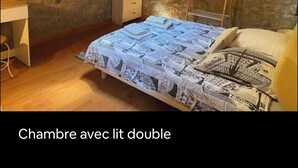 Ein Schlafzimmer mit einem Doppelbett, einem Schreibtisch und einer Steinwand.