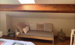 Een kamer met een tweepersoonsbed en een klein bed voor een kind, in een kamer met open structuur.