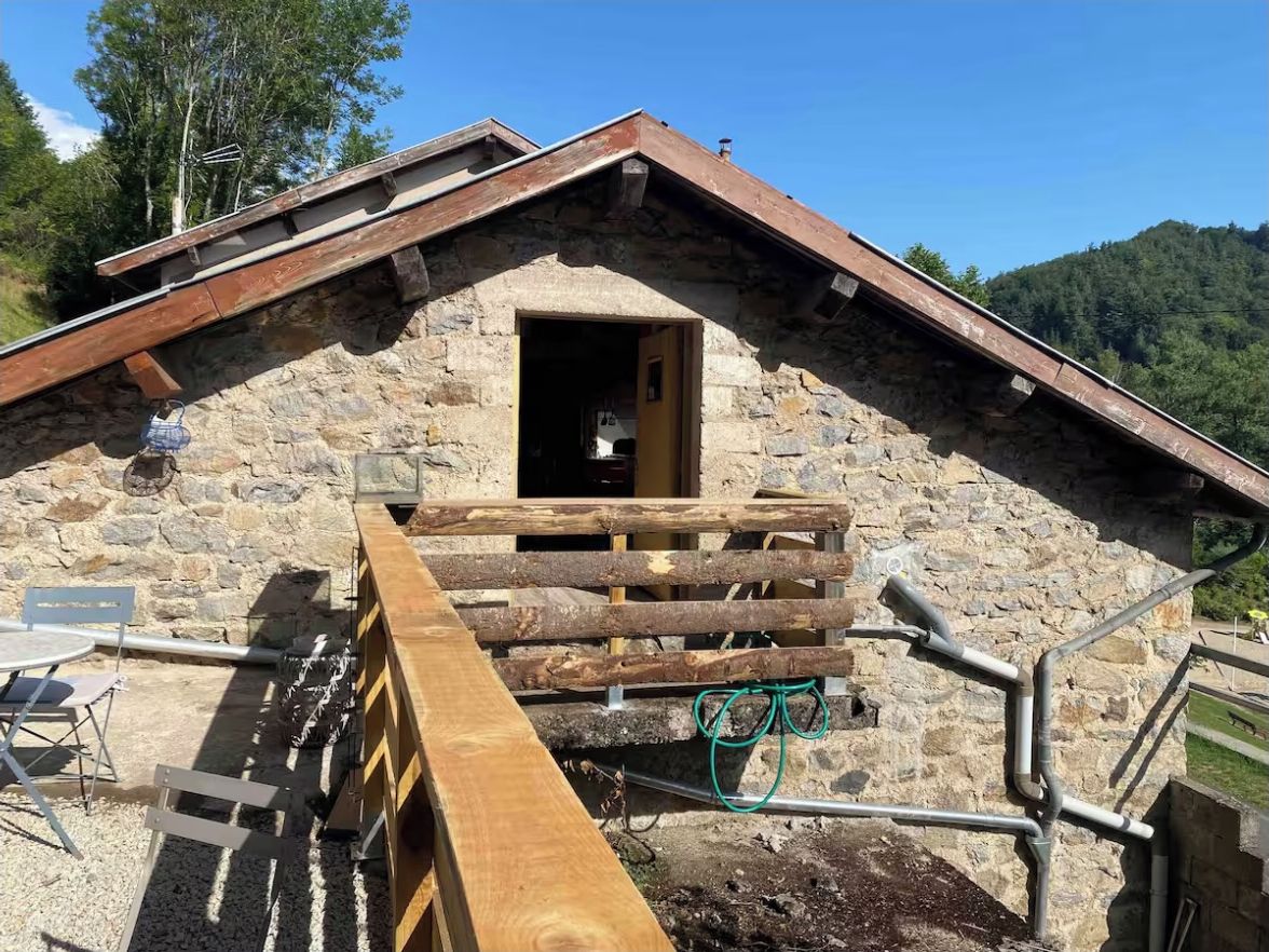 Un bâtiment en pierre avec une rampe en bois menant à une porte ouverte.