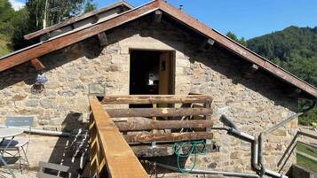 Un bâtiment en pierre avec une rampe en bois menant à une porte ouverte.