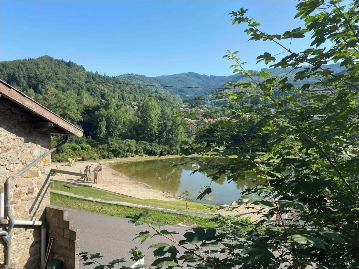 A stone building with a view of a lake and forested hills.