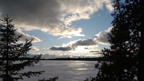 A lake surrounded by trees with a cloudy sky above.