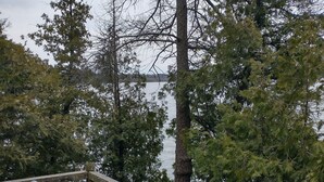 A wooden deck with a railing overlooking a body of water, surrounded by trees.