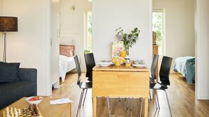 Een moderne woonkamer met een bank, een eettafel met stoelen en een salontafel met een kom en een schaakbord.