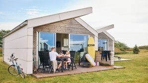 Een modern huis met een terras, een eethoek en een surfboard.
