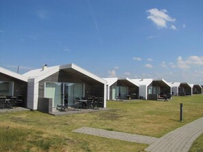 A row of modern, single-story buildings with large windows and outdoor seating areas.