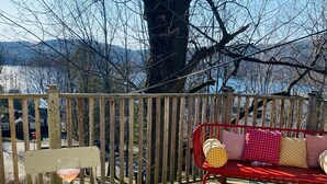 A wooden deck with a table and chairs, a red bench, and a board game.