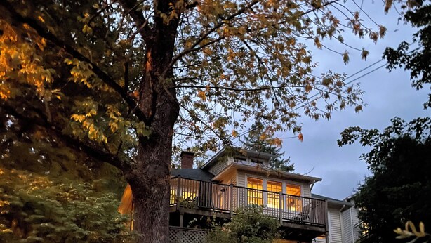 A house with a balcony, surrounded by trees and rocks.
