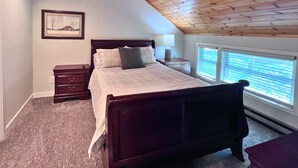 A bedroom with a wooden ceiling, a bed with pillows, a nightstand, a lamp, and a window with blinds. - Cozy Ski-Mountain Getaway (Sugar Mountain)