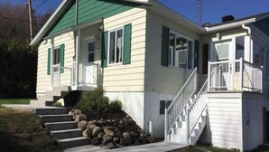 A two-story house with a porch, a staircase, and a small shed.