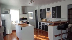 A compact kitchen with a central island, white cabinetry, and a bar area with stools.