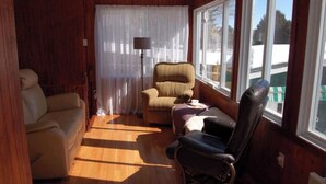 A cozy room with a wooden interior, a beige sofa, a black chair, and a table.