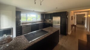 Una cocina moderna con gabinetes oscuros, un refrigerador de acero inoxidable y una encimera de granito.