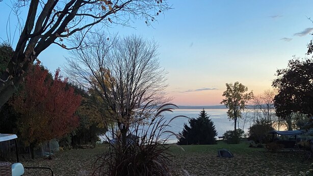 Un hogar con vista a un lago y árboles al fondo.