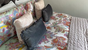 A bed with a floral-patterned duvet, multiple pillows, and a tufted headboard. - Dog friendl near country park and beaches (Brixham)