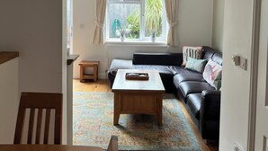 A living room with a sofa, a coffee table, and a window with curtains. - Dog friendl near country park and beaches (Brixham)