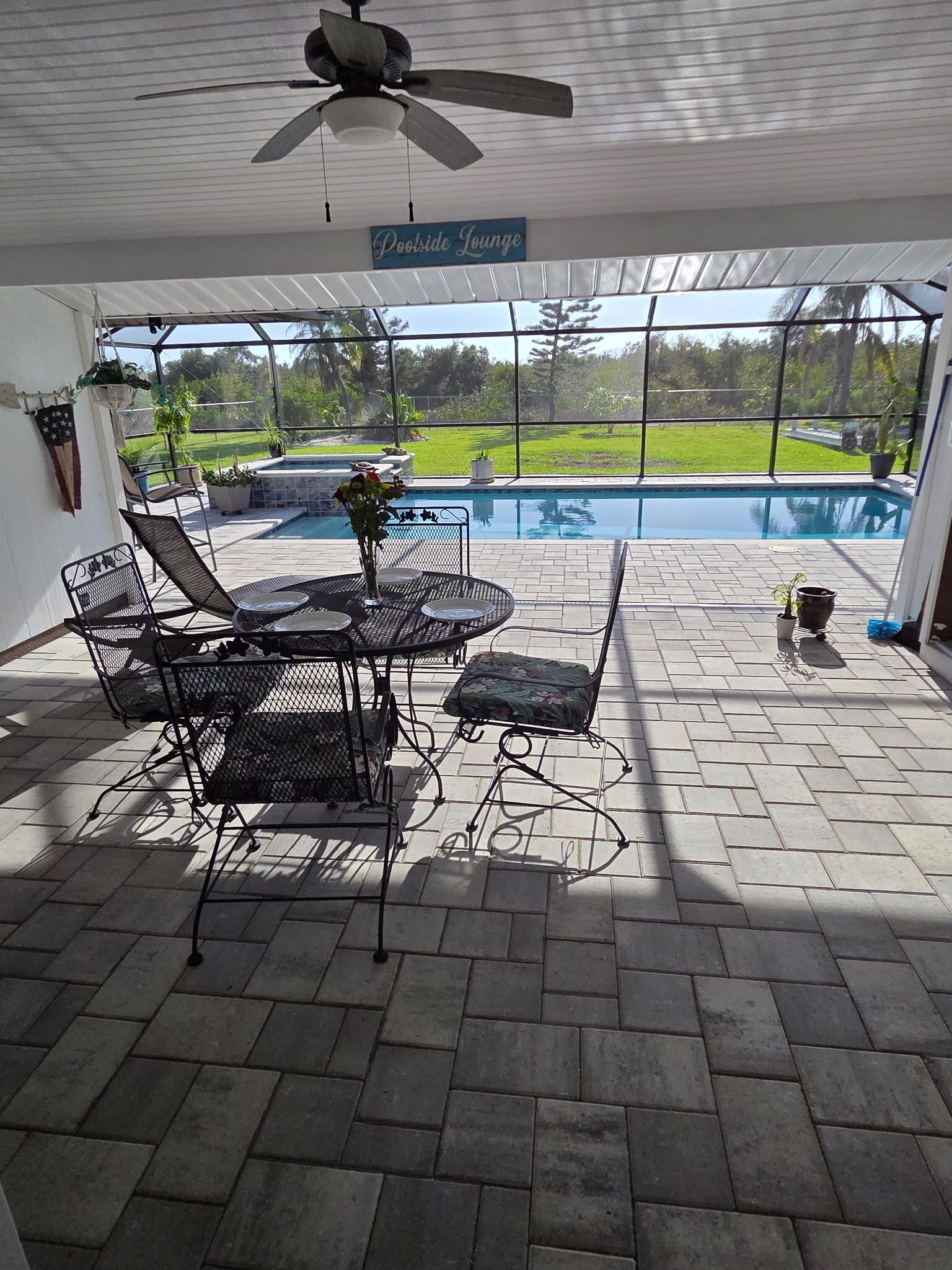 Un patio couvert avec une piscine, des chaises longues et un ventilateur de plafond.