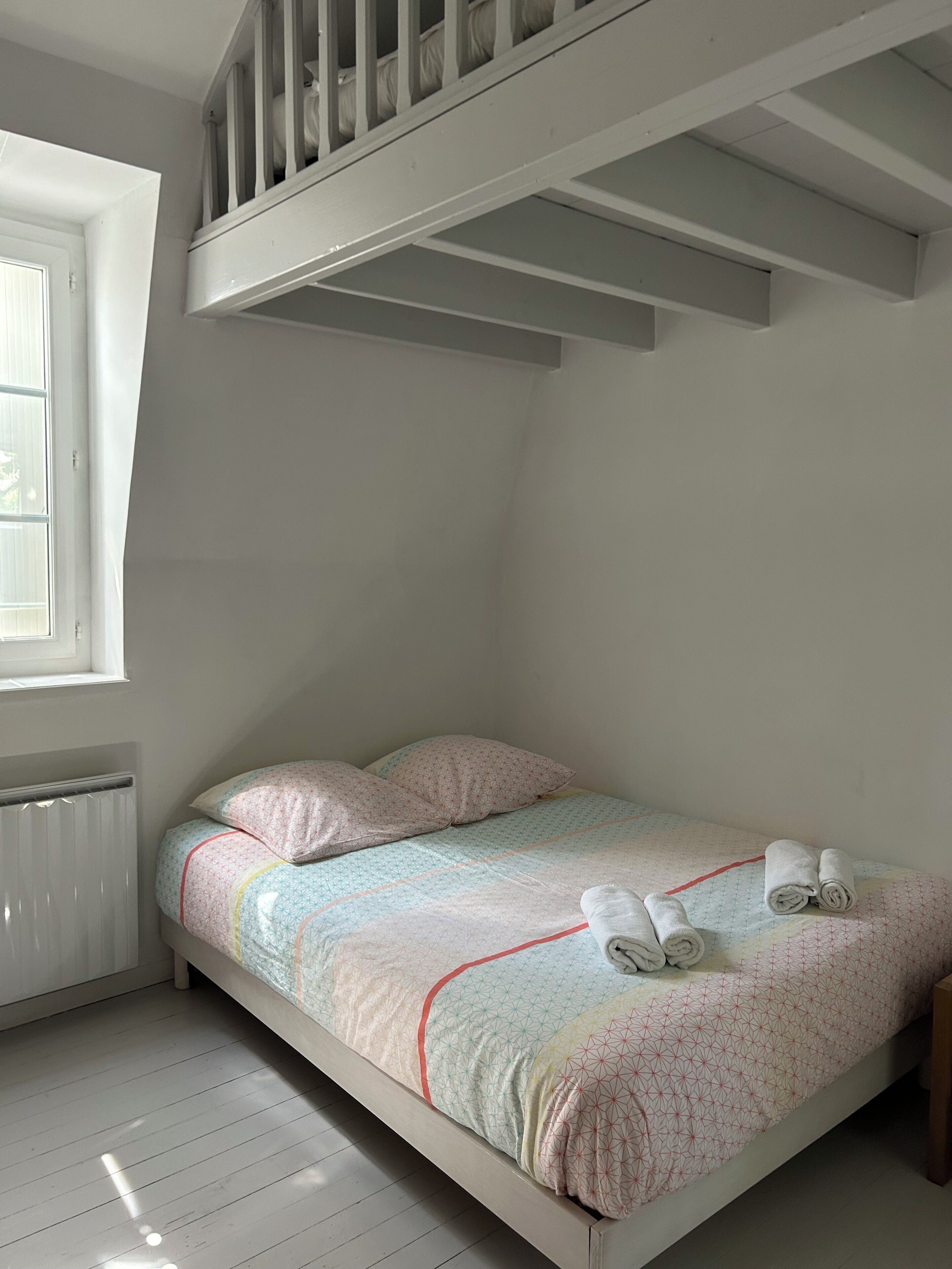 Une chambre avec un lit superposé, une fenêtre et un radiateur.