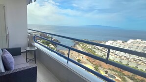 A balcony with a view of the sea and a distant mountain.