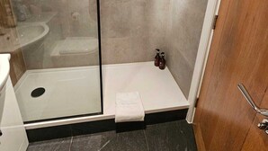 Ein modernes Badezimmer mit Duschkabine aus Glas, einem weißen Waschbecken und einer Holztür.