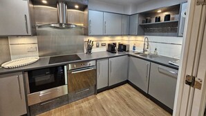 Eine moderne Küche mit Edelstahlgeräten, grauen Schränken und Holzboden.