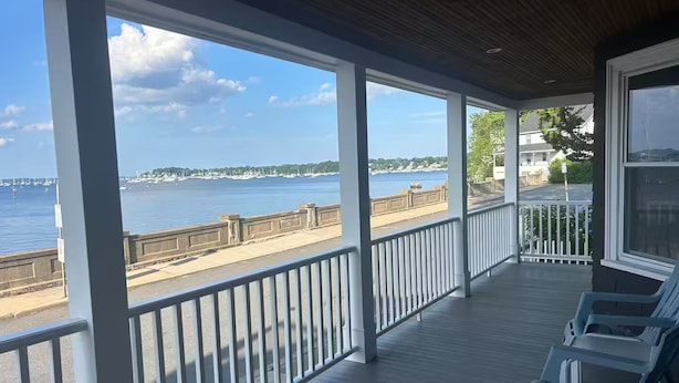 A covered outdoor area with a view of the sea, a wooden deck, and a railing. - Waterfront 2 Bedroom Unit (Salem)